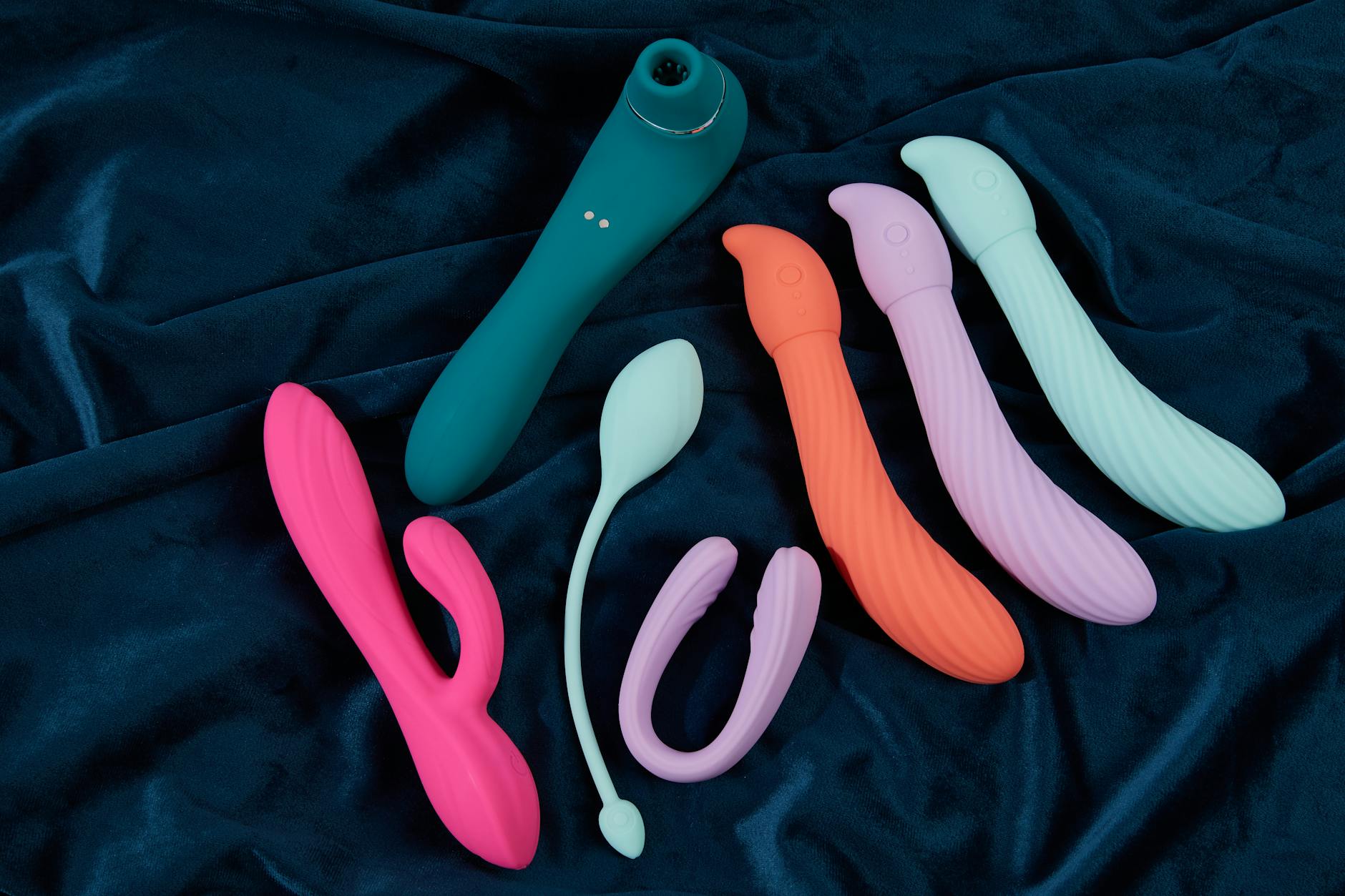 Pink vibrator on purple background with heart confetti and candles, symbolizing intimate relaxation