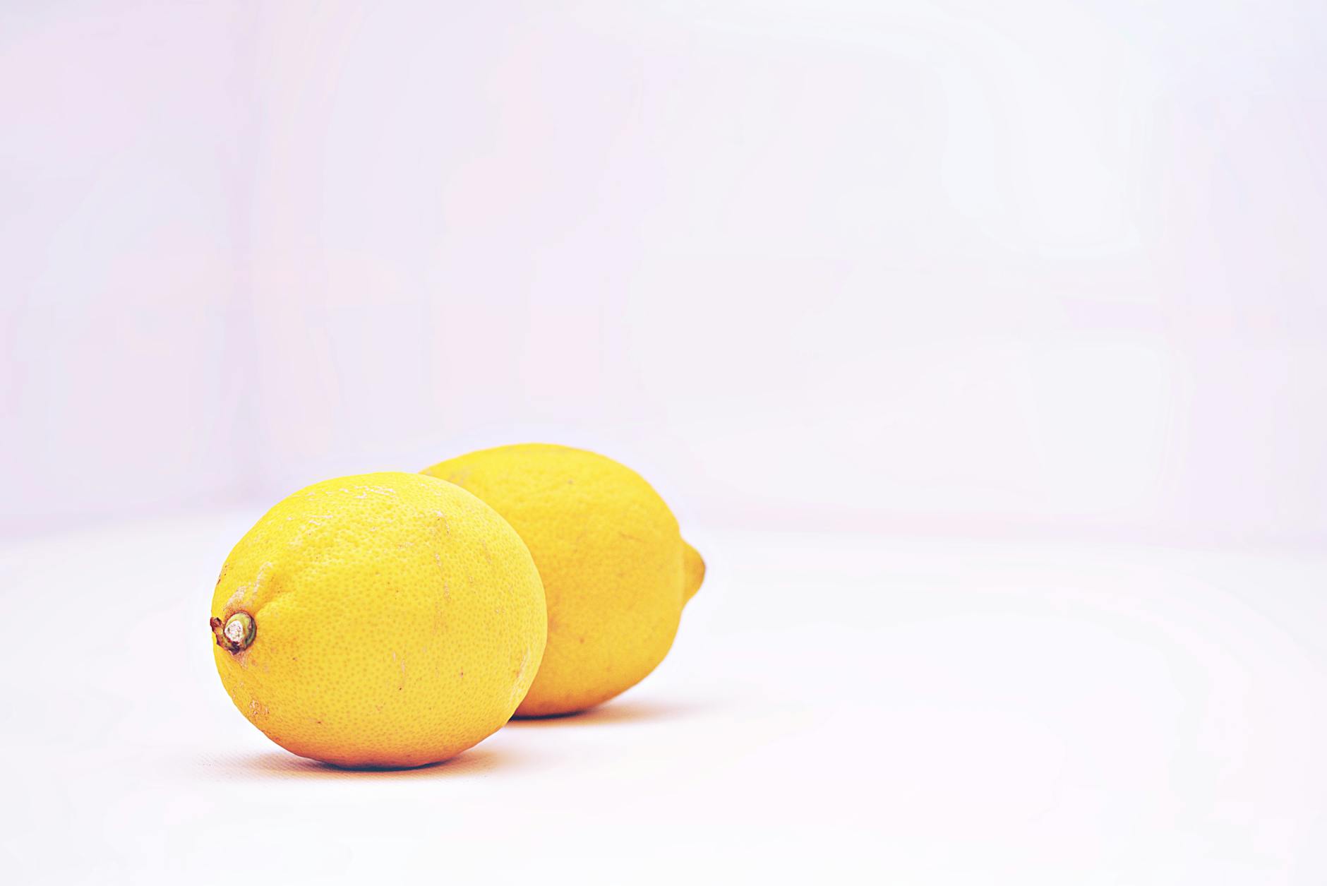 Hand holding a blue silicone lemon vibrator against a purple background