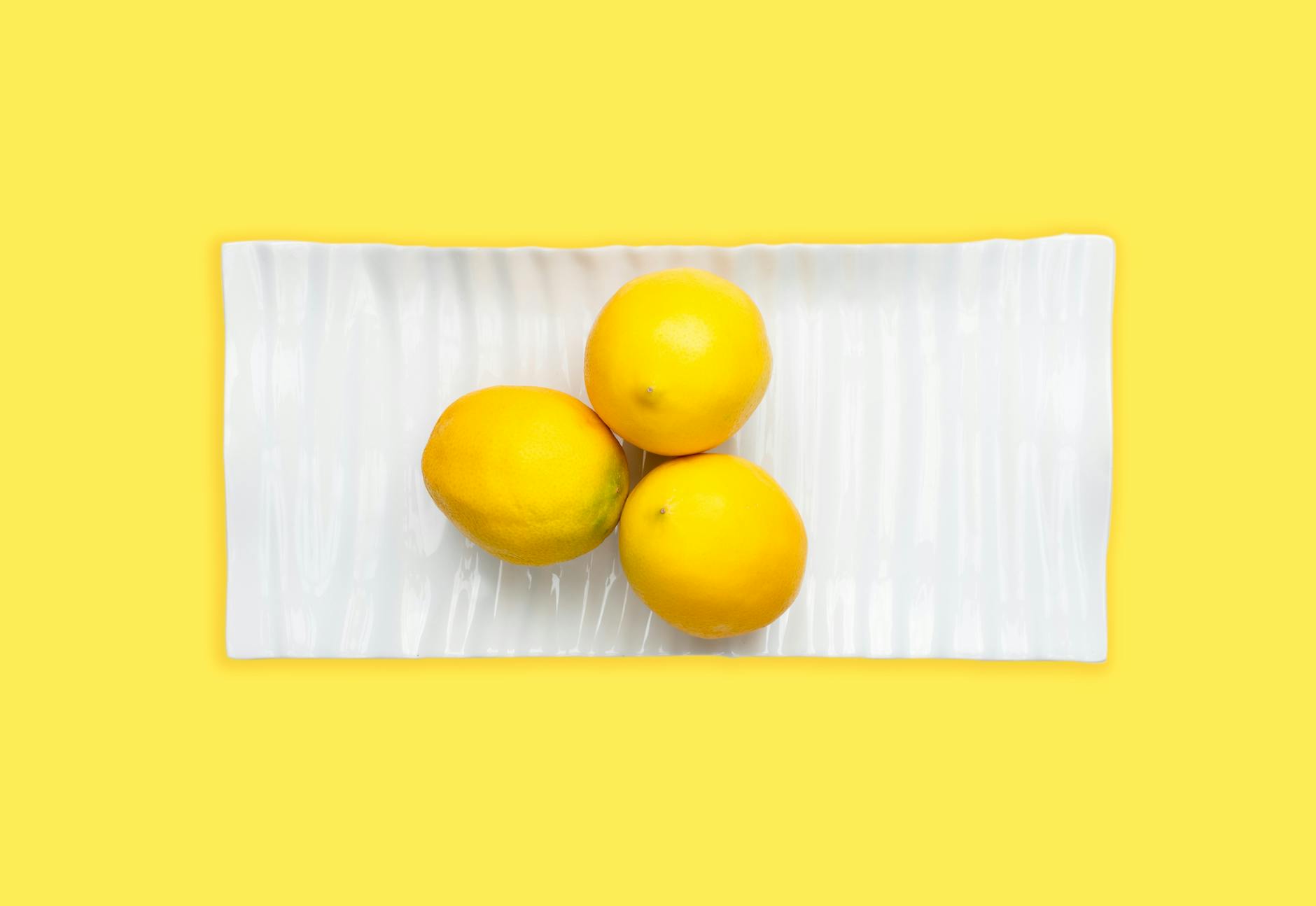 Blue vibrator surrounded by flowers and citrus slices on a bright yellow background, representing reconnection to pleasure