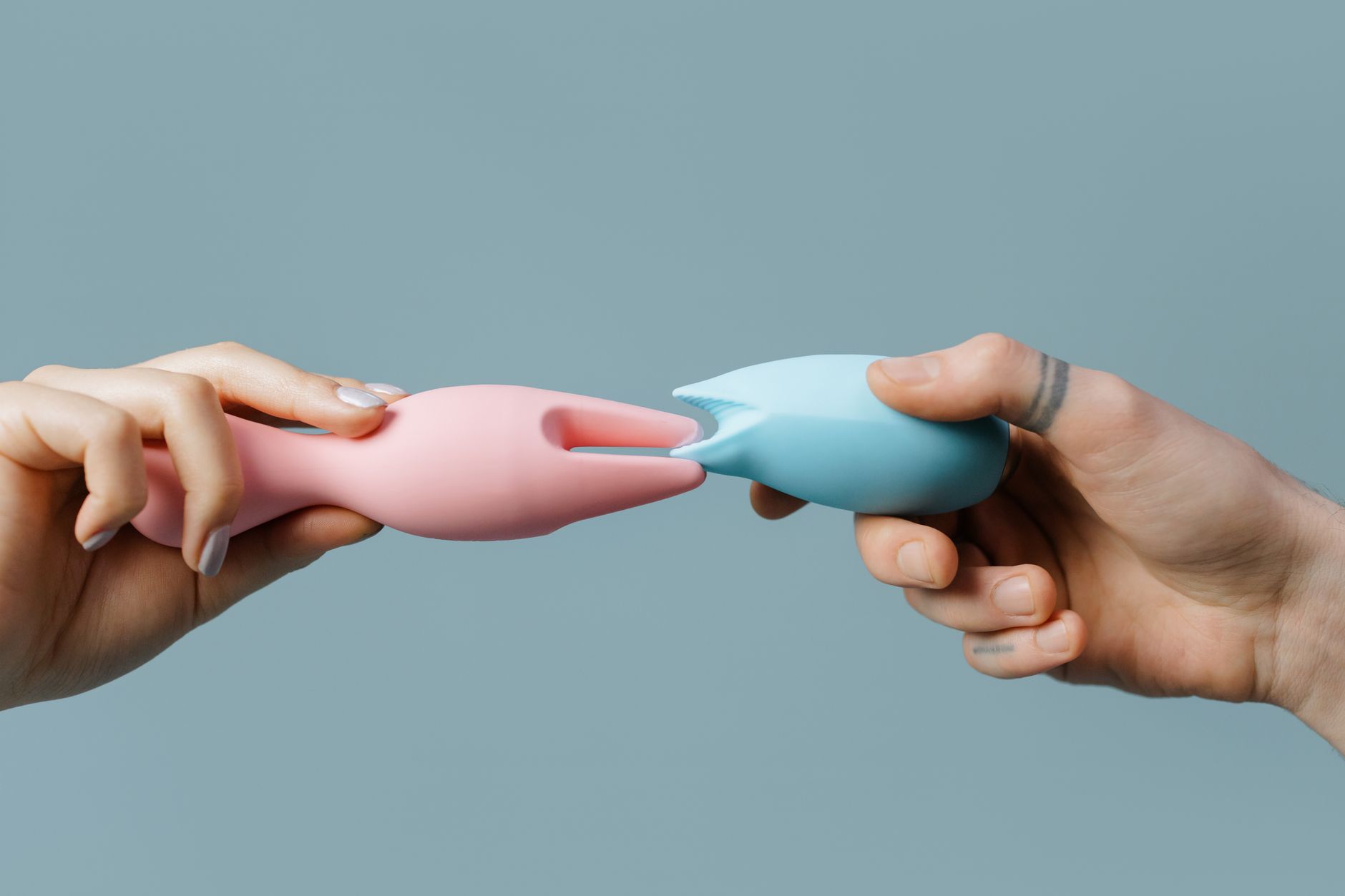 Woman holding a pink clitoral vibrator with art and books in the background