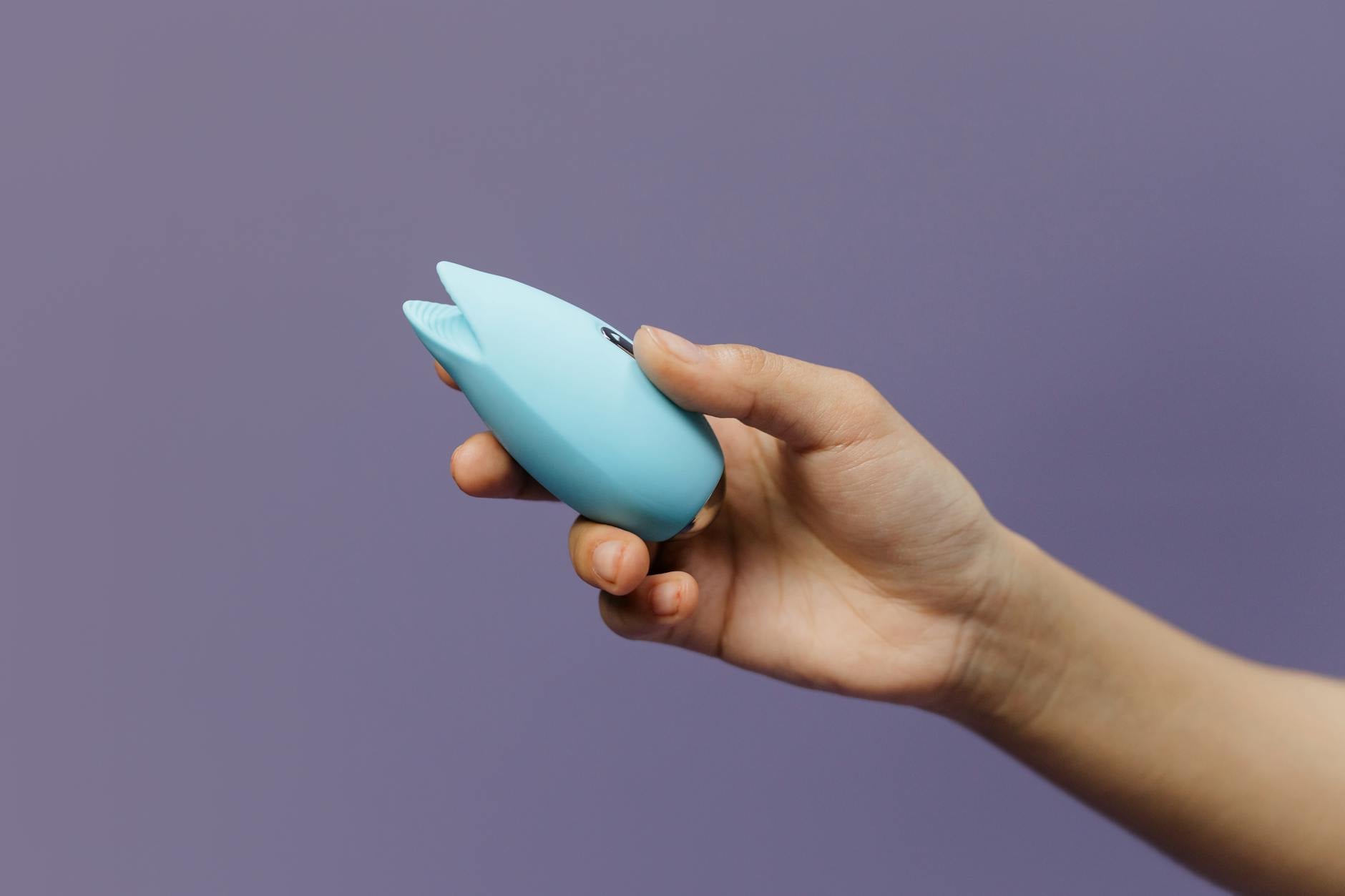 Blue silicone lemon vibrator held in hand against purple background, representing reclaiming pleasure without pressure