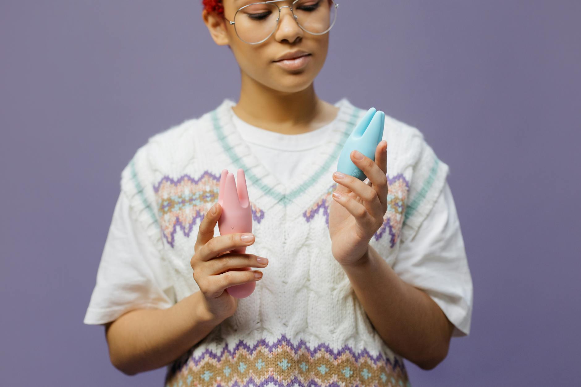 Woman holding silicone clitoral vibrators in thoughtful contemplation